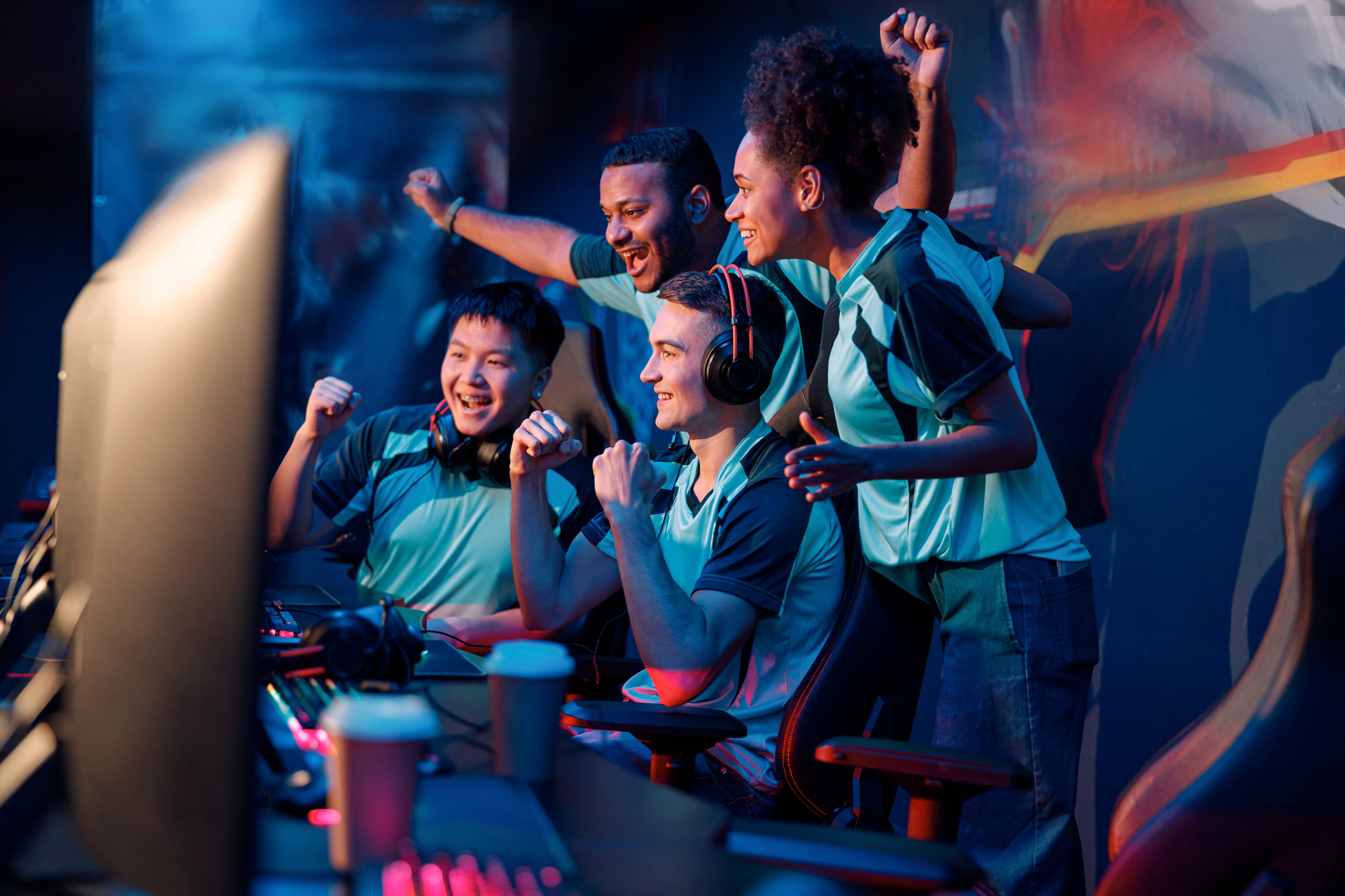 Group of diverse young gamers celebrating enthusiastically while playing video games.