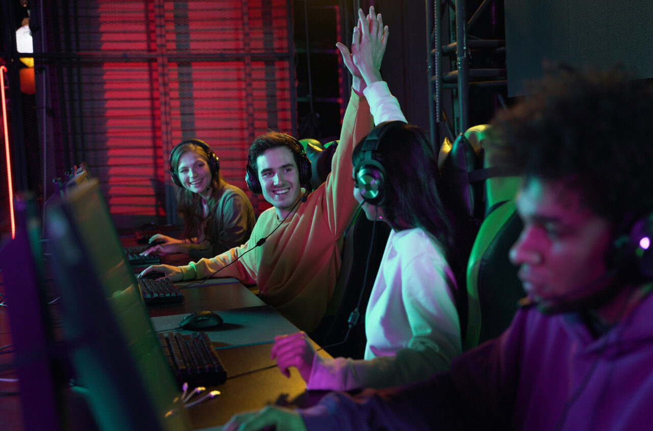 Team of diverse game developers working on computers in neon lit room